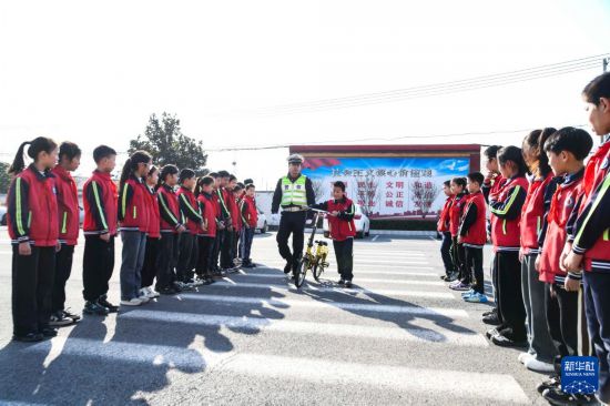 12月2日，在河南省濟(jì)源市五龍口鎮(zhèn)實(shí)驗(yàn)小學(xué)，濟(jì)源市公安局交通警察支隊(duì)的民警指導(dǎo)小學(xué)生安全過(guò)“斑馬線”。新華社發(fā)（苗秋鬧攝）