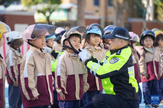 12月2日，在浙江省湖州市德清縣鐘管鎮(zhèn)中心幼兒園，鐘管鎮(zhèn)交警中隊(duì)民警指導(dǎo)孩子們?nèi)绾握_佩戴安全頭盔。新華社發(fā)（王正攝）