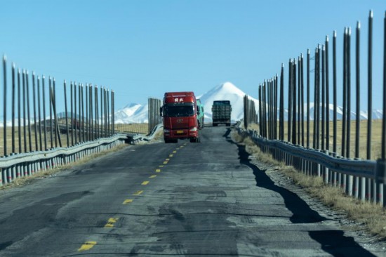 貨車從兩側(cè)遍布熱棒的青藏公路一段經(jīng)過（12月2日攝）。新華社記者 姜帆 攝