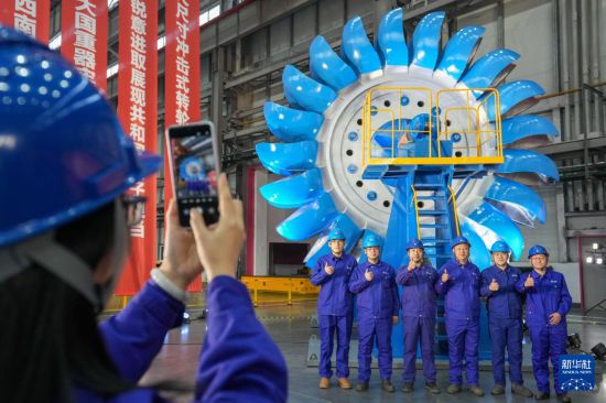 12月30日，在哈電集團(tuán)哈爾濱電機(jī)廠有限責(zé)任公司生產(chǎn)車(chē)間，工作人員在沖擊式水輪機(jī)轉(zhuǎn)輪前合影留念。新華社記者 王建威 攝